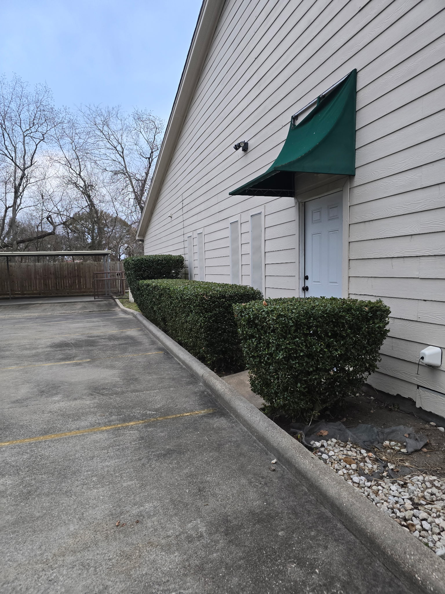 Trimmed hedge line and cleaned property edge beside a building