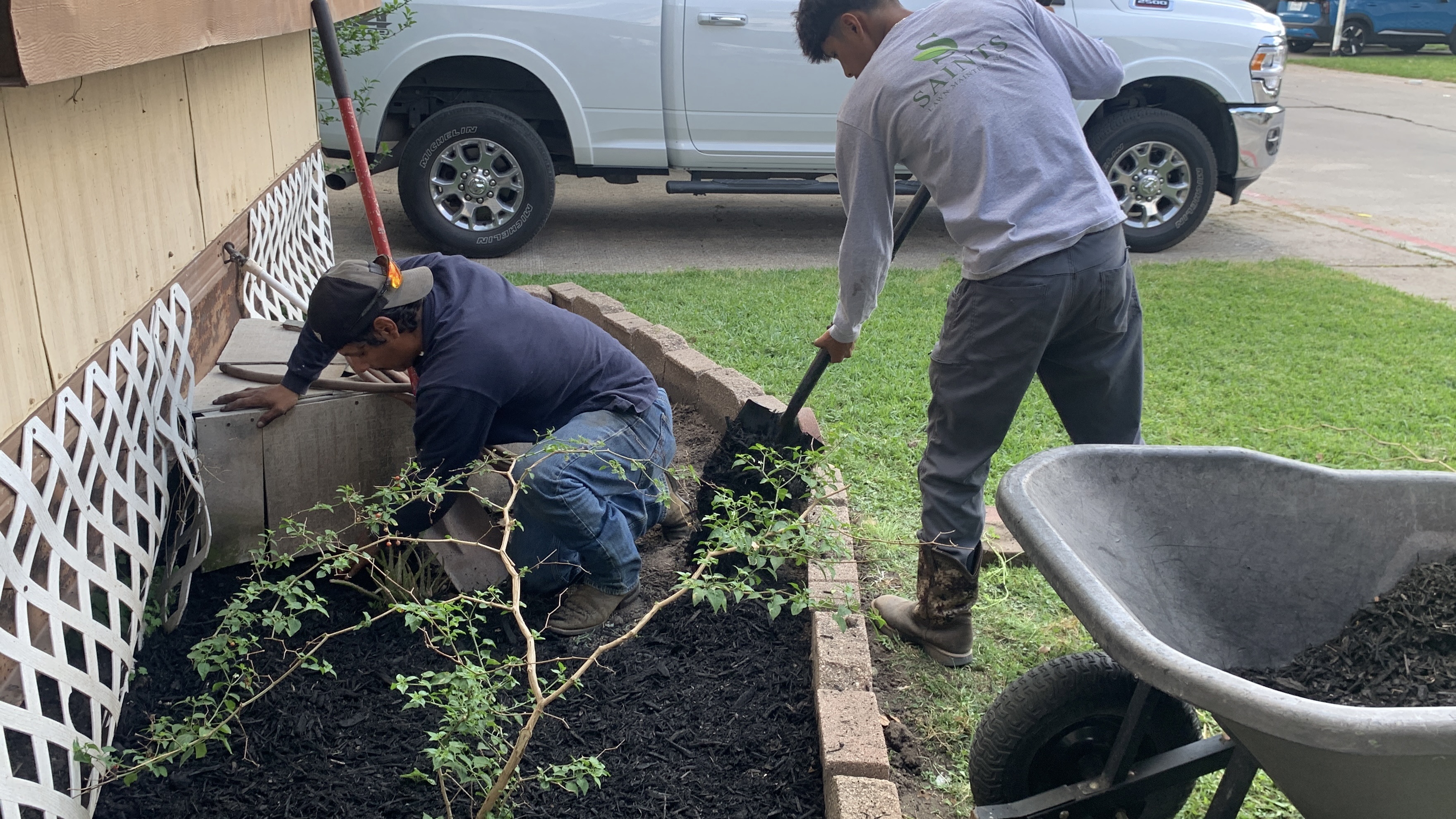Saints Lawn Maintenance team refreshing a flower bed with mulch